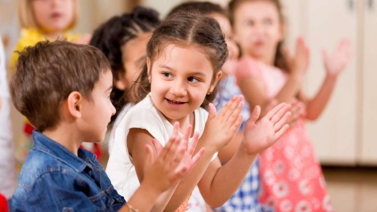 Preschool children clapping hands in classroom activity.